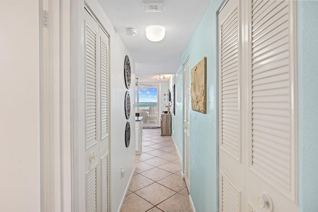 corridor with light tile patterned floors and baseboards