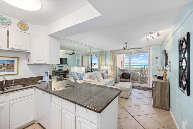 kitchen with white cabinets, open floor plan, a peninsula, white dishwasher, and a sink