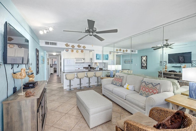 living room featuring light tile patterned floors, visible vents, and a ceiling fan