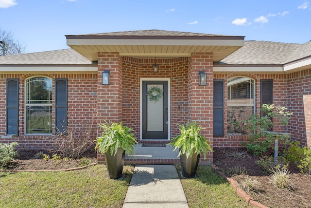 entrance to property with brick siding and a shingled roof