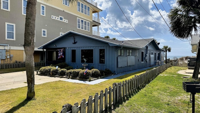 view of front of property with board and batten siding, a front lawn, and fence