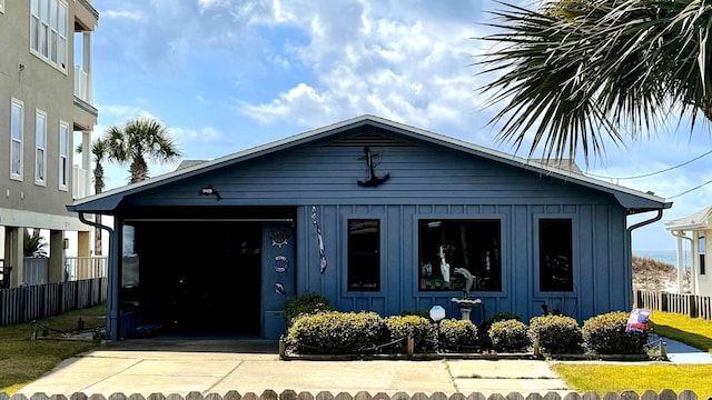 bungalow-style house featuring an attached garage, board and batten siding, driveway, and fence