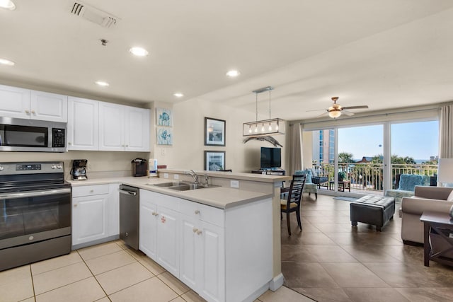 kitchen with visible vents, open floor plan, a peninsula, stainless steel appliances, and a sink