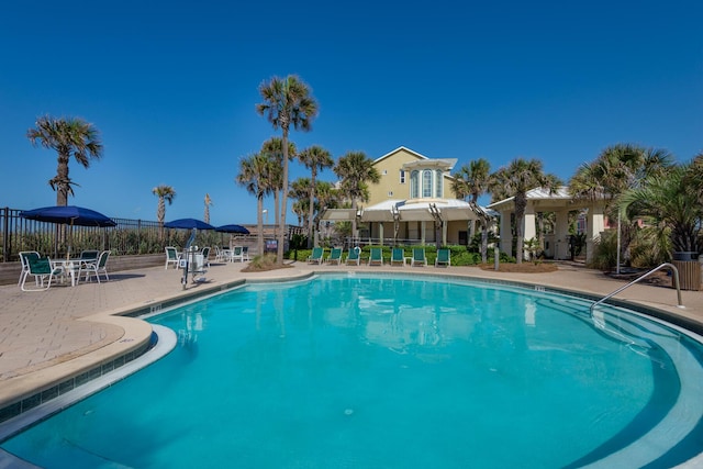 community pool with a patio area and fence