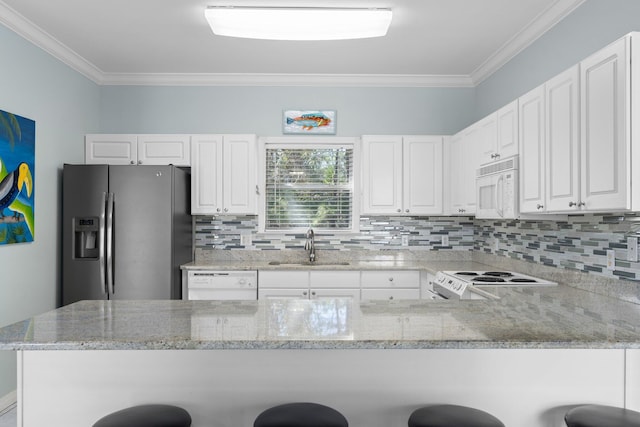 kitchen with ornamental molding, white appliances, a sink, and a peninsula