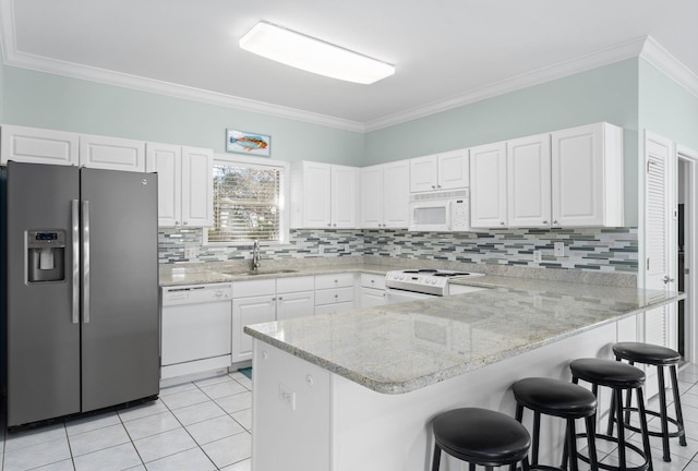 kitchen with light tile patterned floors, a sink, light stone countertops, white appliances, and a peninsula