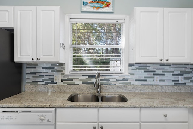 kitchen featuring white dishwasher, decorative backsplash, white cabinets, and a sink