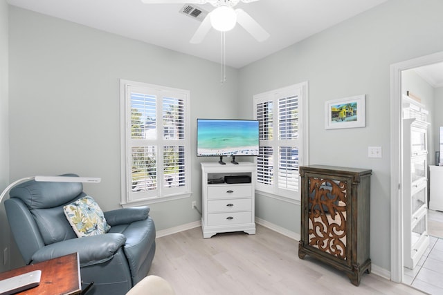 living area with light wood finished floors, baseboards, visible vents, and a ceiling fan