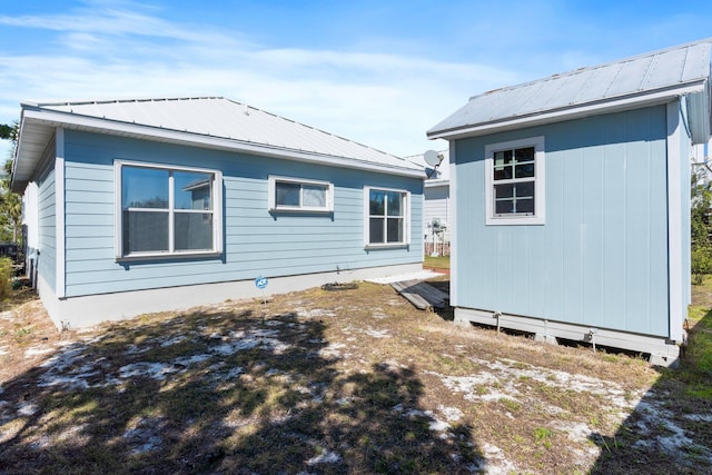 rear view of property featuring an outbuilding and metal roof