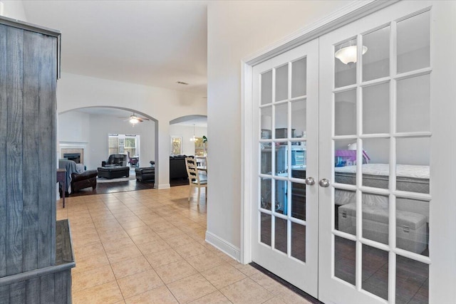 hall with arched walkways, french doors, tile patterned flooring, and baseboards