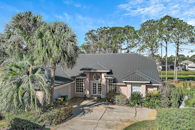 view of front of house featuring an attached garage, french doors, driveway, and stucco siding