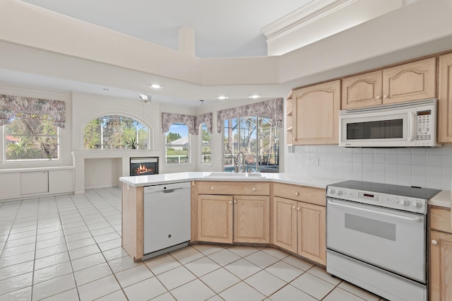 kitchen with light brown cabinetry, white appliances, tasteful backsplash, and a sink