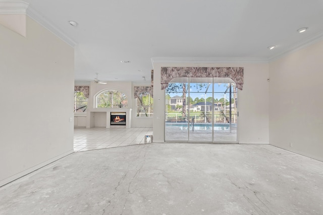 unfurnished living room featuring a wealth of natural light, unfinished concrete flooring, a ceiling fan, and ornamental molding