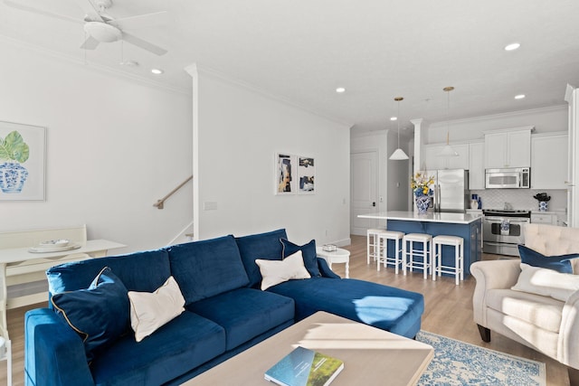 living area with recessed lighting, ceiling fan, stairs, ornamental molding, and light wood-type flooring