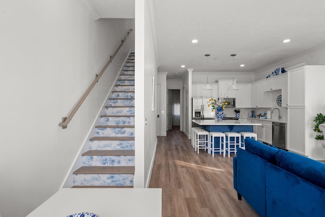 living area featuring wood finished floors, beverage cooler, stairs, and ornamental molding