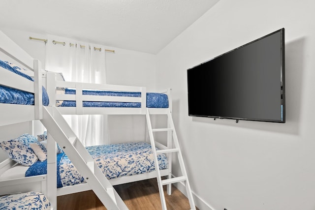 bedroom with baseboards, a textured ceiling, and wood finished floors