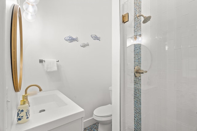 bathroom with vanity, toilet, baseboards, and tiled shower