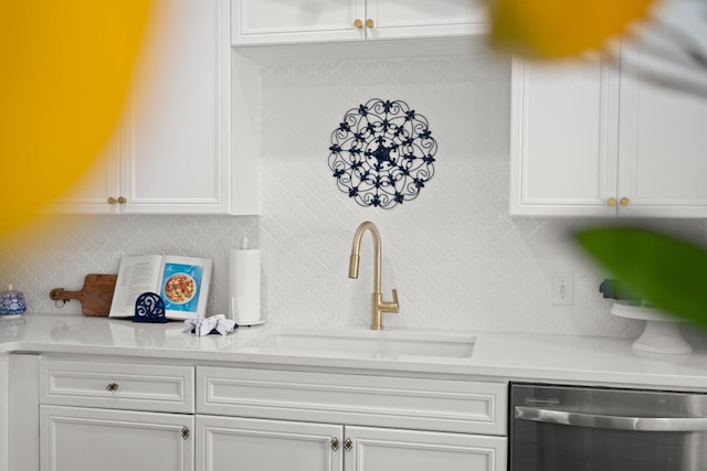 kitchen featuring a sink, tasteful backsplash, stainless steel dishwasher, and white cabinetry