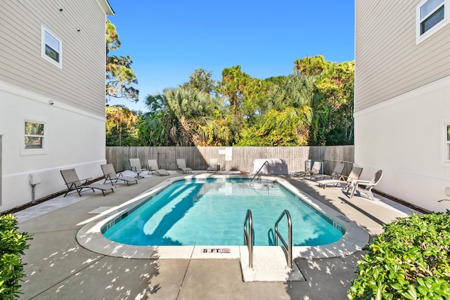 community pool with a patio area and a fenced backyard