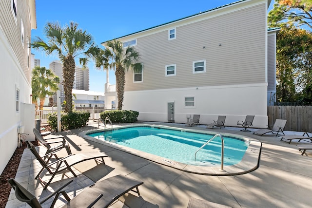 pool with a patio area and fence