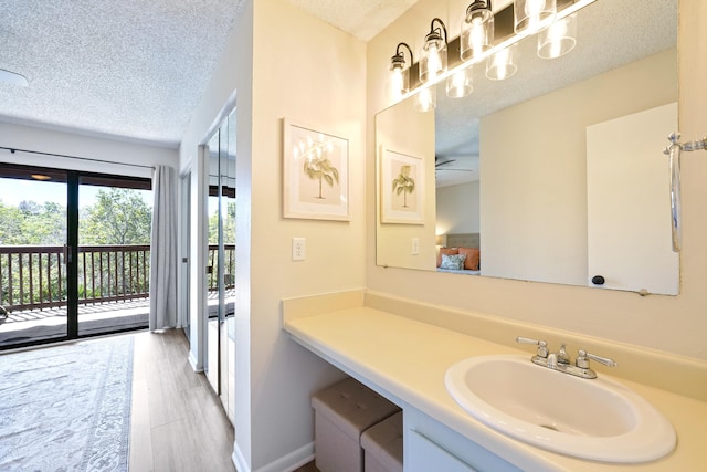 bathroom with baseboards, a textured ceiling, vanity, and wood finished floors