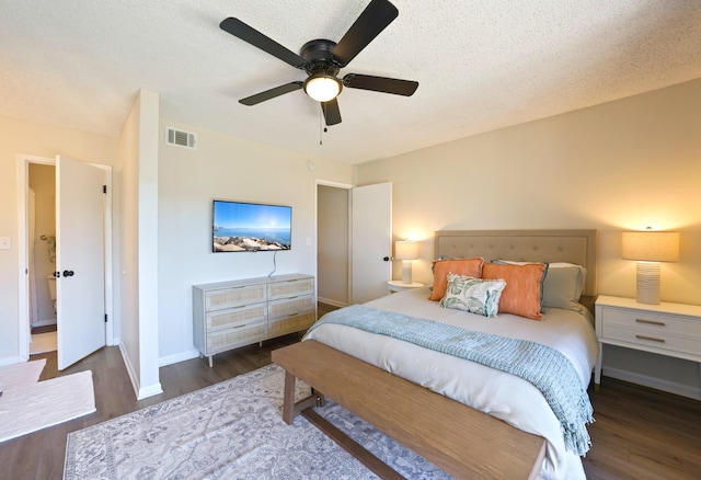 bedroom featuring baseboards, a textured ceiling, visible vents, and wood finished floors