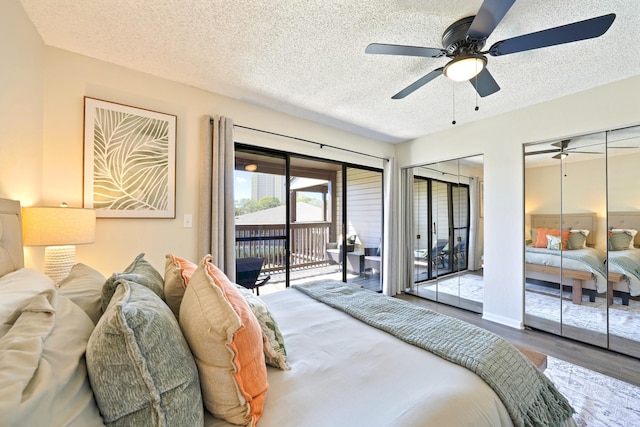 bedroom with ceiling fan, wood finished floors, access to exterior, a textured ceiling, and two closets