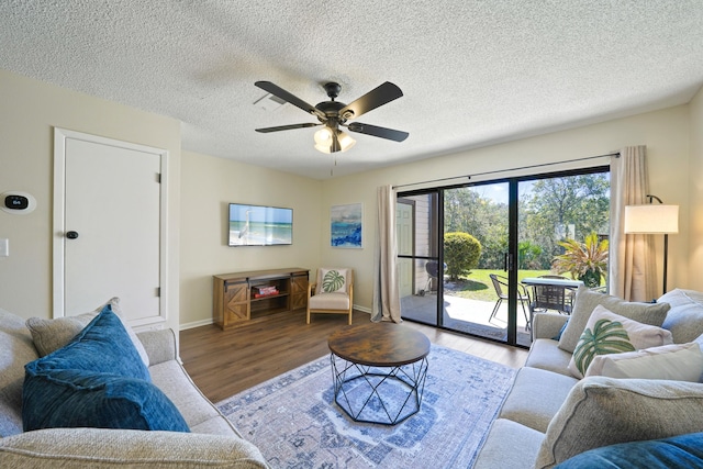 living room with ceiling fan, a textured ceiling, baseboards, and wood finished floors