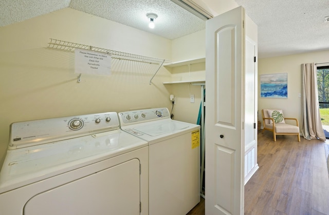 laundry area featuring laundry area, a textured ceiling, separate washer and dryer, and wood finished floors