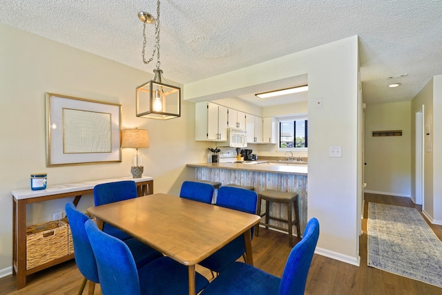 dining room with dark wood-style floors, a textured ceiling, and baseboards