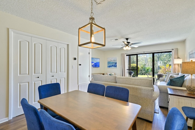 dining room with a textured ceiling, wood finished floors, visible vents, and a ceiling fan