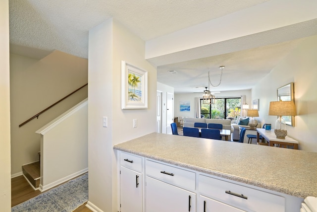 kitchen with white cabinets, light countertops, a textured ceiling, and wood finished floors