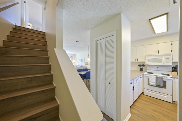 staircase featuring a textured ceiling, visible vents, and wood finished floors