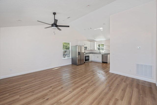 unfurnished living room featuring ceiling fan, visible vents, baseboards, vaulted ceiling, and light wood-style floors