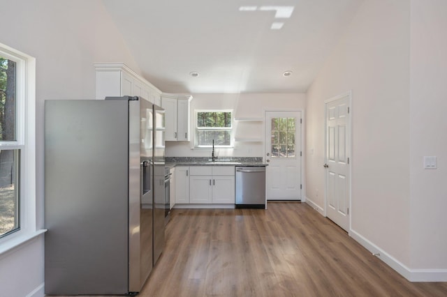 kitchen featuring stainless steel appliances, white cabinetry, a sink, and open shelves