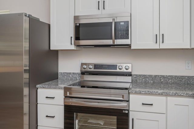 kitchen with stainless steel appliances, white cabinetry, and light stone countertops