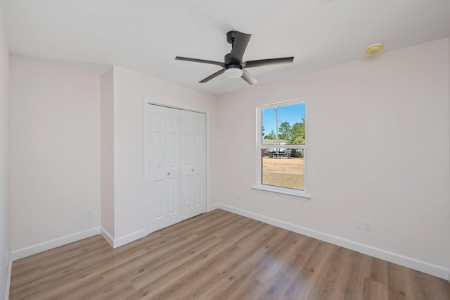 unfurnished bedroom featuring ceiling fan, a closet, light wood-type flooring, and baseboards