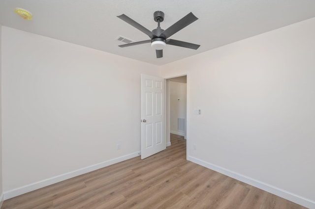 spare room featuring light wood-style flooring, visible vents, and baseboards