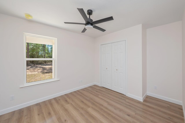 unfurnished bedroom with a ceiling fan, light wood-type flooring, a closet, and baseboards