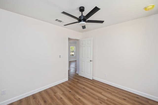 unfurnished room featuring baseboards, visible vents, ceiling fan, and wood finished floors