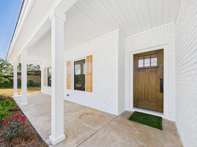 doorway to property featuring a patio and brick siding