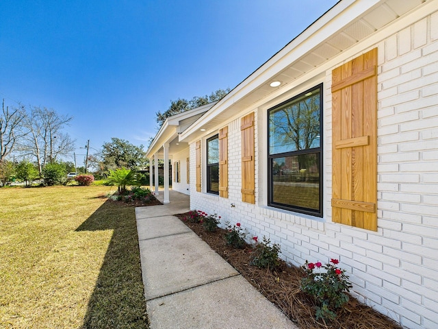 view of side of home with brick siding and a lawn