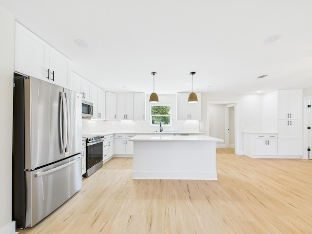 kitchen featuring white cabinetry, stainless steel appliances, light wood-style floors, and a sink