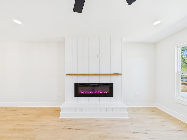 unfurnished living room featuring a ceiling fan, wood finished floors, baseboards, recessed lighting, and a large fireplace