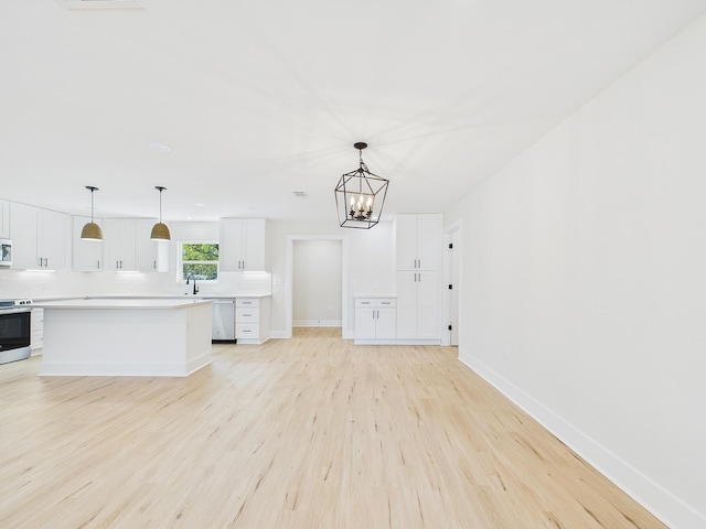 kitchen with light countertops, light wood-style flooring, stainless steel appliances, white cabinetry, and a sink