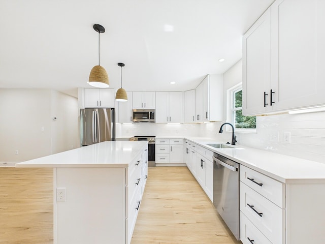 kitchen with light wood-style flooring, a sink, a kitchen island, backsplash, and appliances with stainless steel finishes