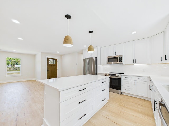 kitchen with a kitchen island, backsplash, stainless steel appliances, and light wood-type flooring