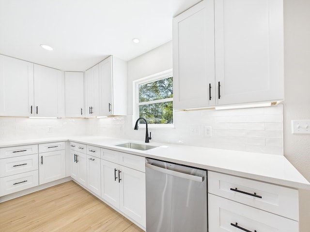 kitchen featuring light wood finished floors, a sink, light countertops, stainless steel dishwasher, and tasteful backsplash