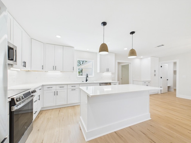 kitchen with visible vents, light wood-style flooring, a sink, white cabinets, and appliances with stainless steel finishes