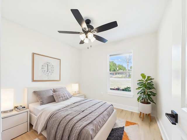 bedroom featuring baseboards, light wood-style floors, and ceiling fan